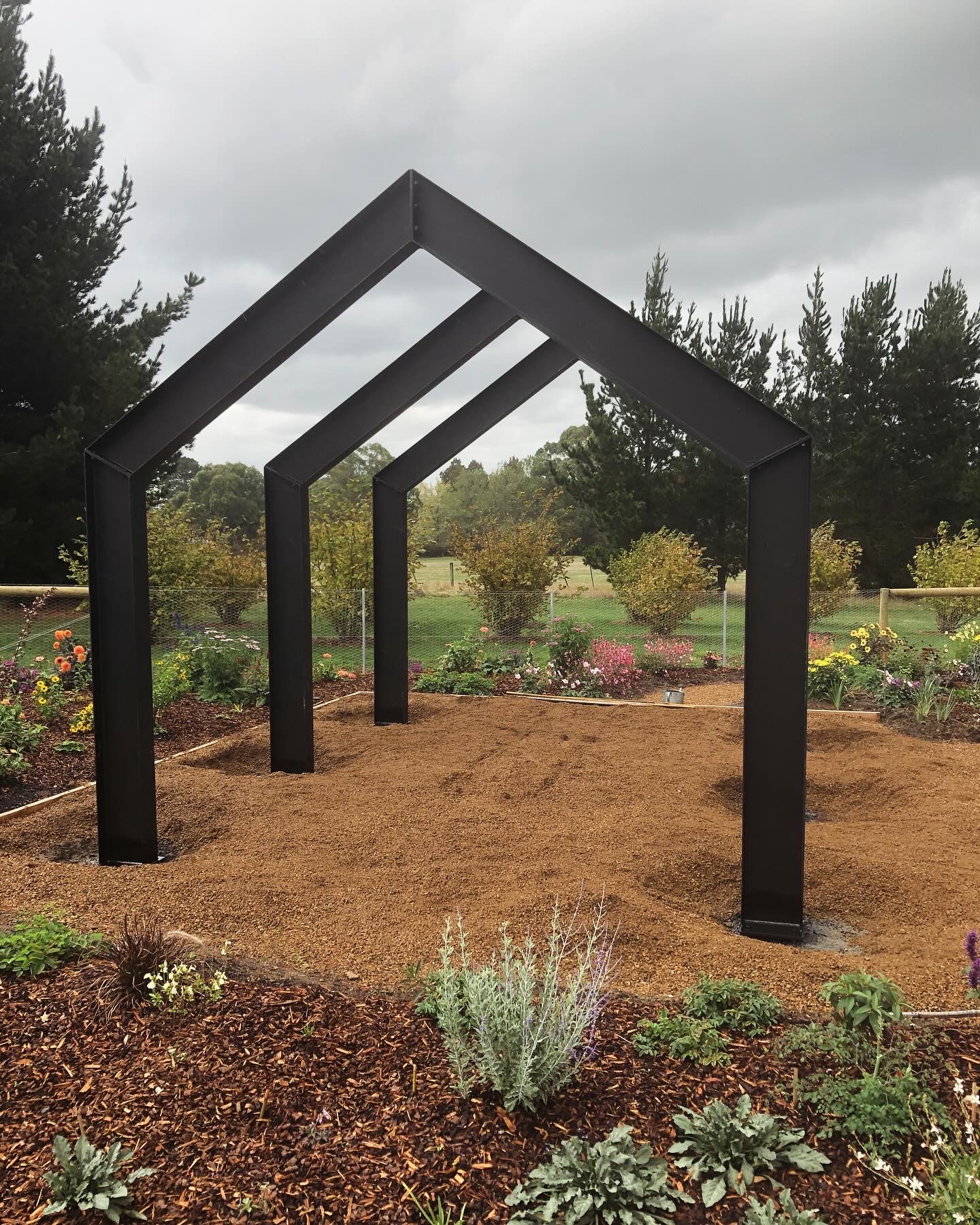 Black steel arbour frames in landscaped garden