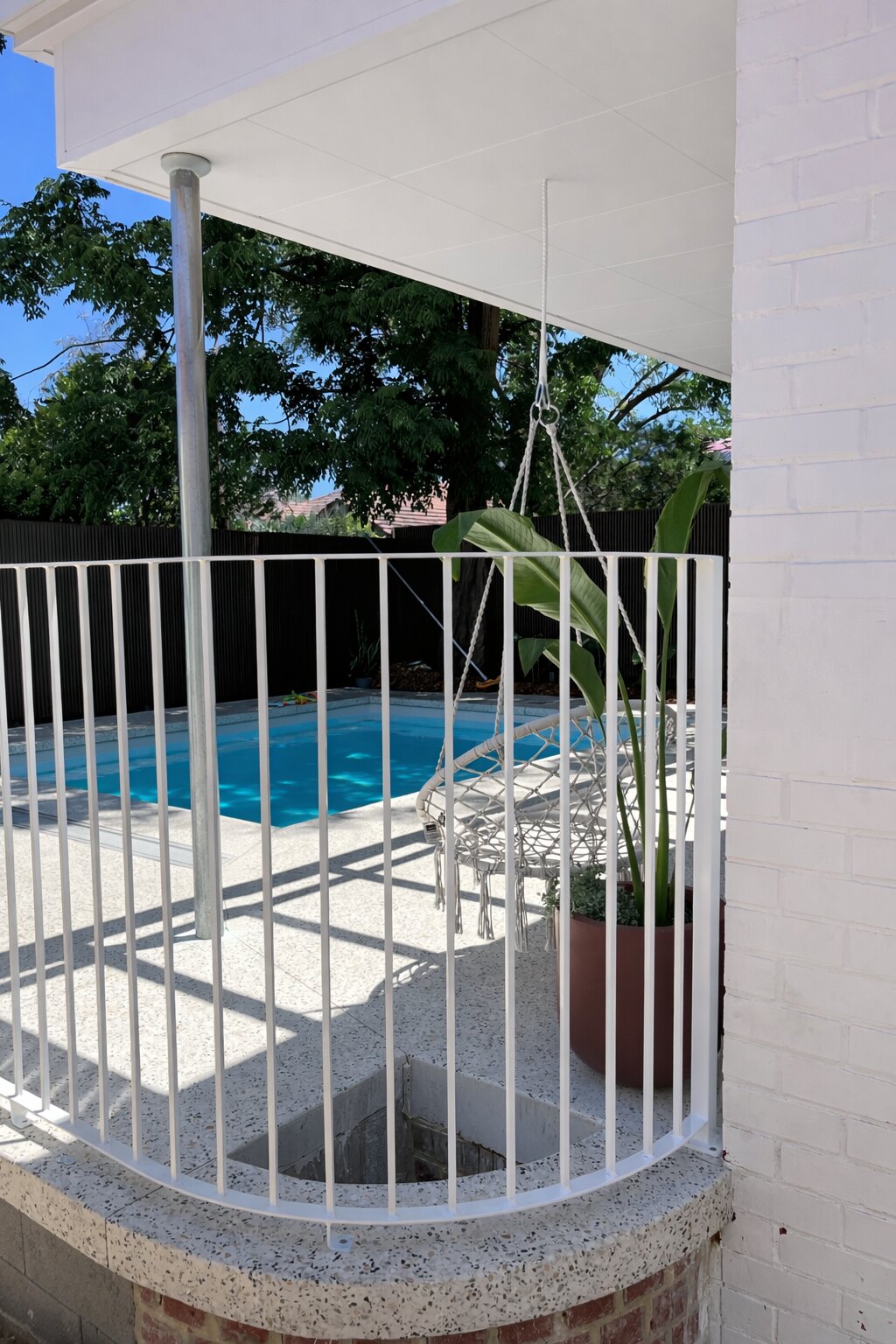 Curved white pool fencing under a finished patio roof